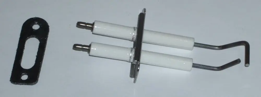 Zündelektrodenblock von Daikin mit zwei weißen Elektroden und einer metallischen Halterung, daneben eine schwarze Platte mit ovalem Ausschnitt.